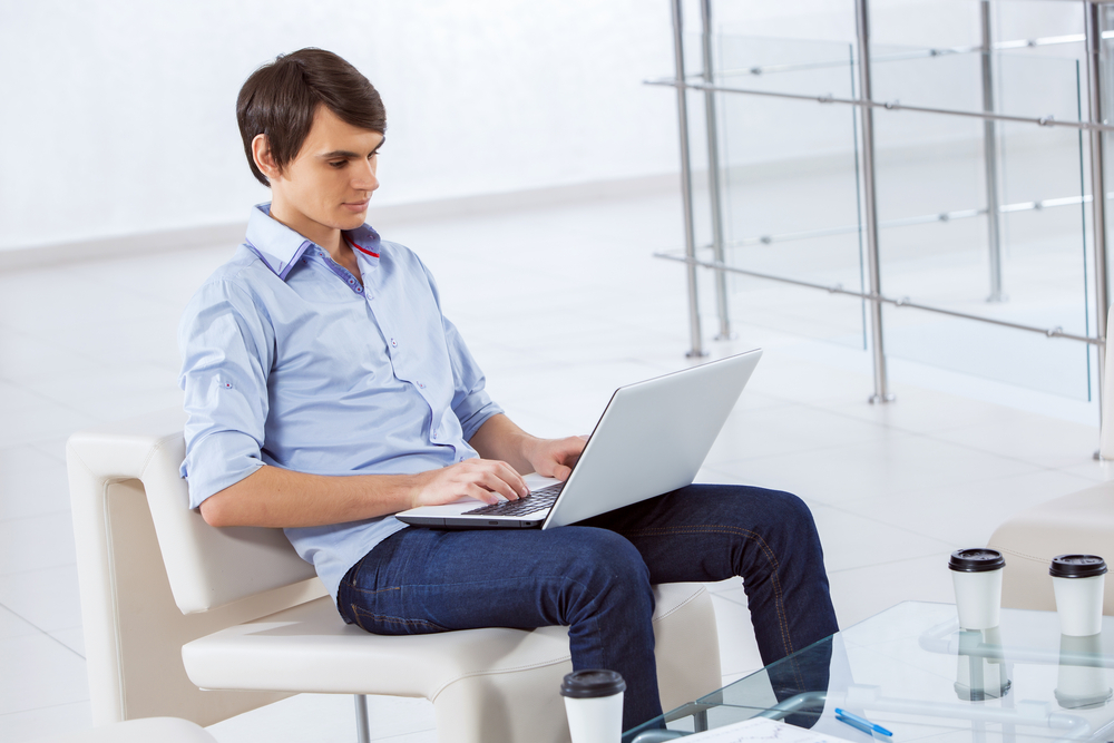 Young handsome businessman sitting and using laptop-1